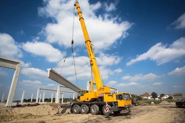 Guindaste JK Locações realizando içamento de viga em obra industrial